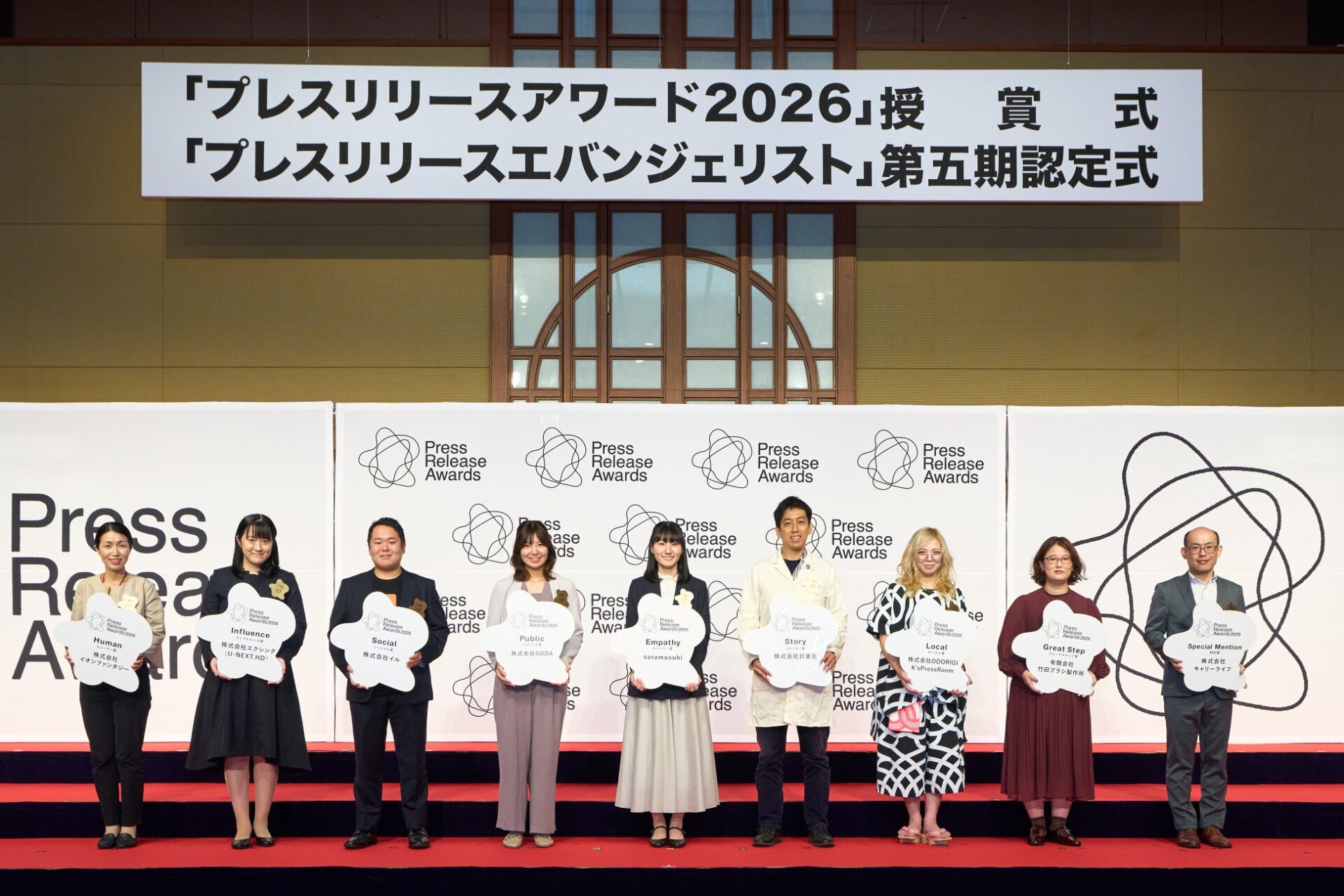 ステージ上に受賞者たちが並び、受賞プレートを掲げて登壇している表彰式の記念撮影