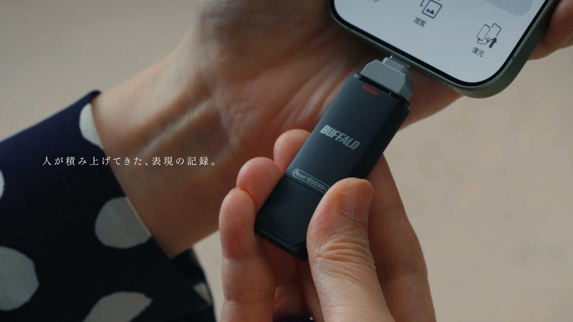 スマートフォンの端子に挿入されたスティック型機器の手元