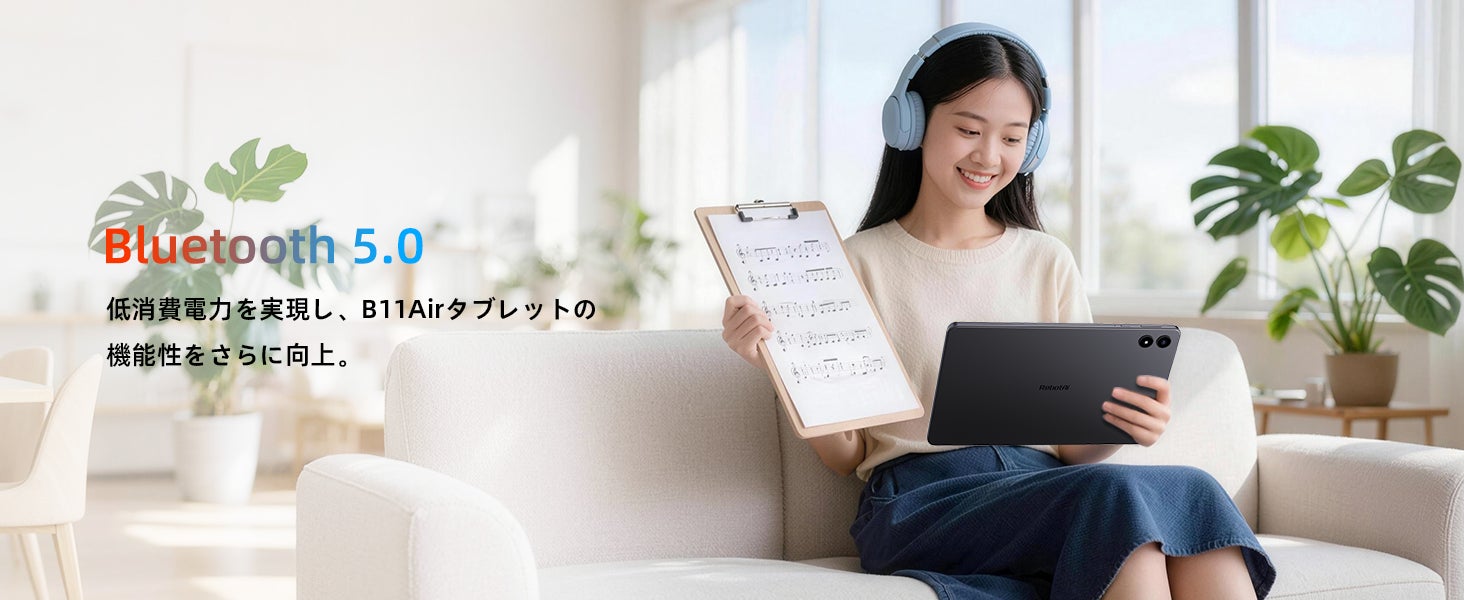ヘッドホンを装着してソファに座り、タブレットとバインダーを持つ人物の写真
