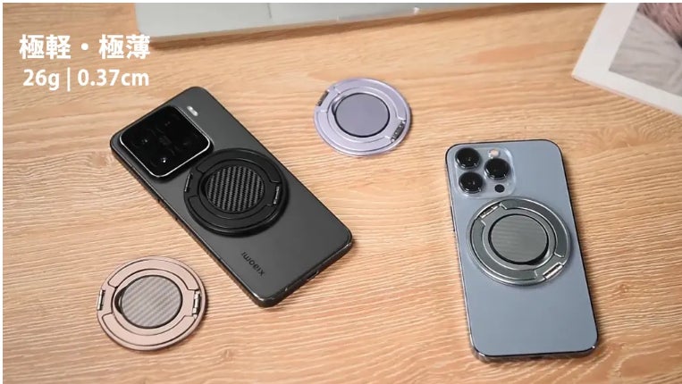木目調の机の上に置かれたスマートフォンと複数色の薄型スマホリング