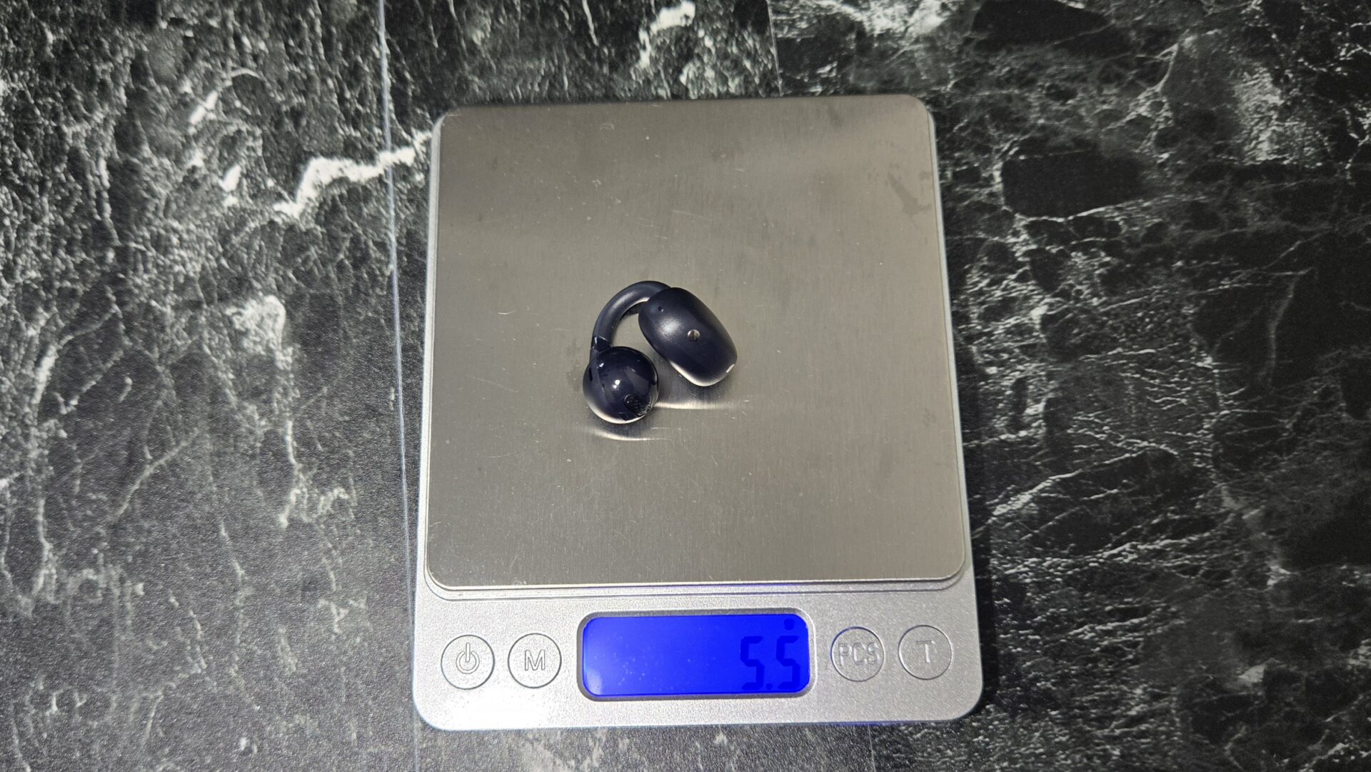 デジタルはかりの上に乗せられた重さ5.5の黒いイヤホン型の物体