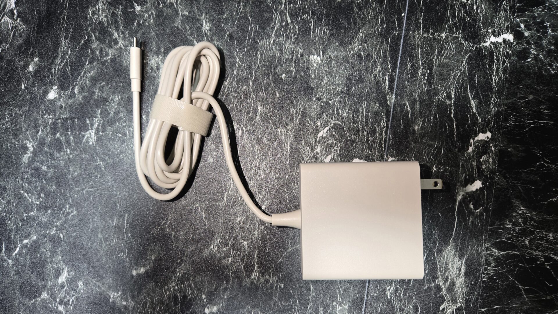 ケーブルバンドでまとめられた淡い色の充電ケーブルと電源アダプター