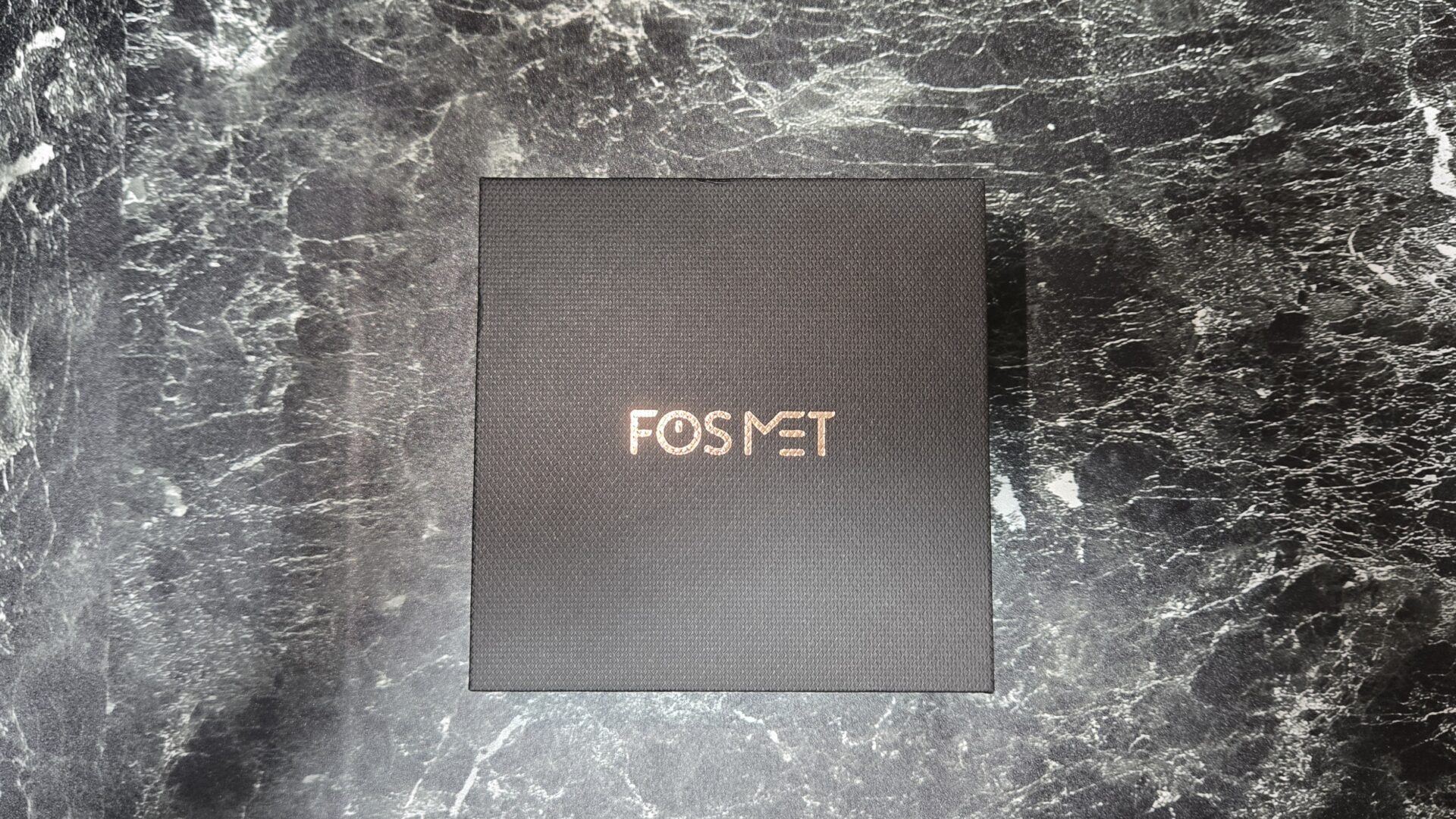 FOSMETのロゴ入り黒い箱が大理石の上に置かれている