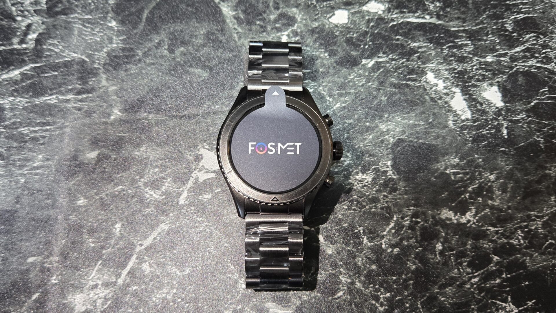 FOSMETロゴ入りの黒い金属バンドのスマートウォッチ