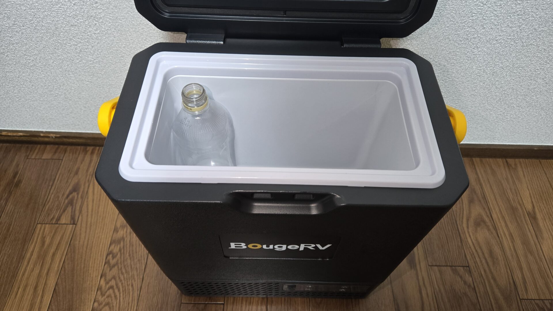 BougeRVの蓋が開いた黒いポータブル冷蔵庫 中に空のペットボトル1本 黄色の取っ手付き