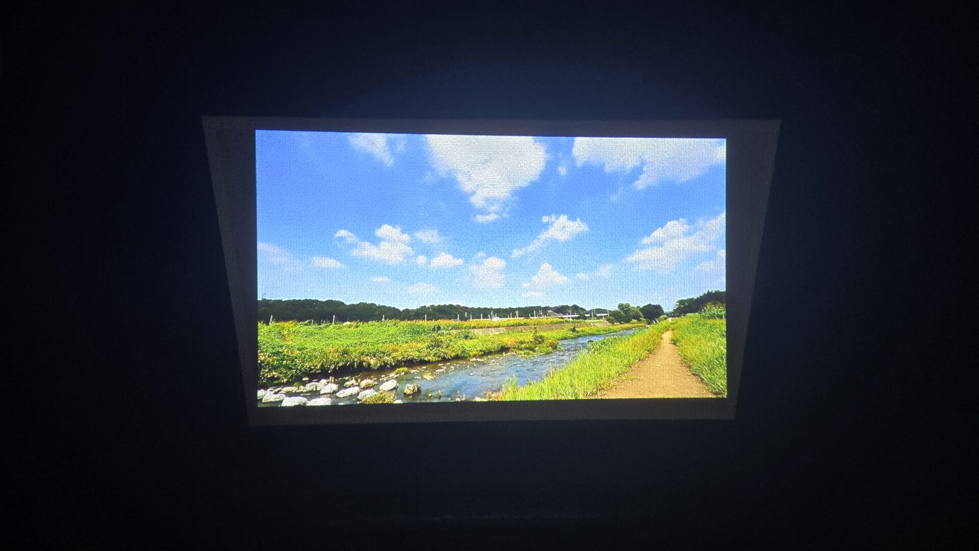 夏の青い空と白い雲 緑豊かな田園を流れる小川と土の道