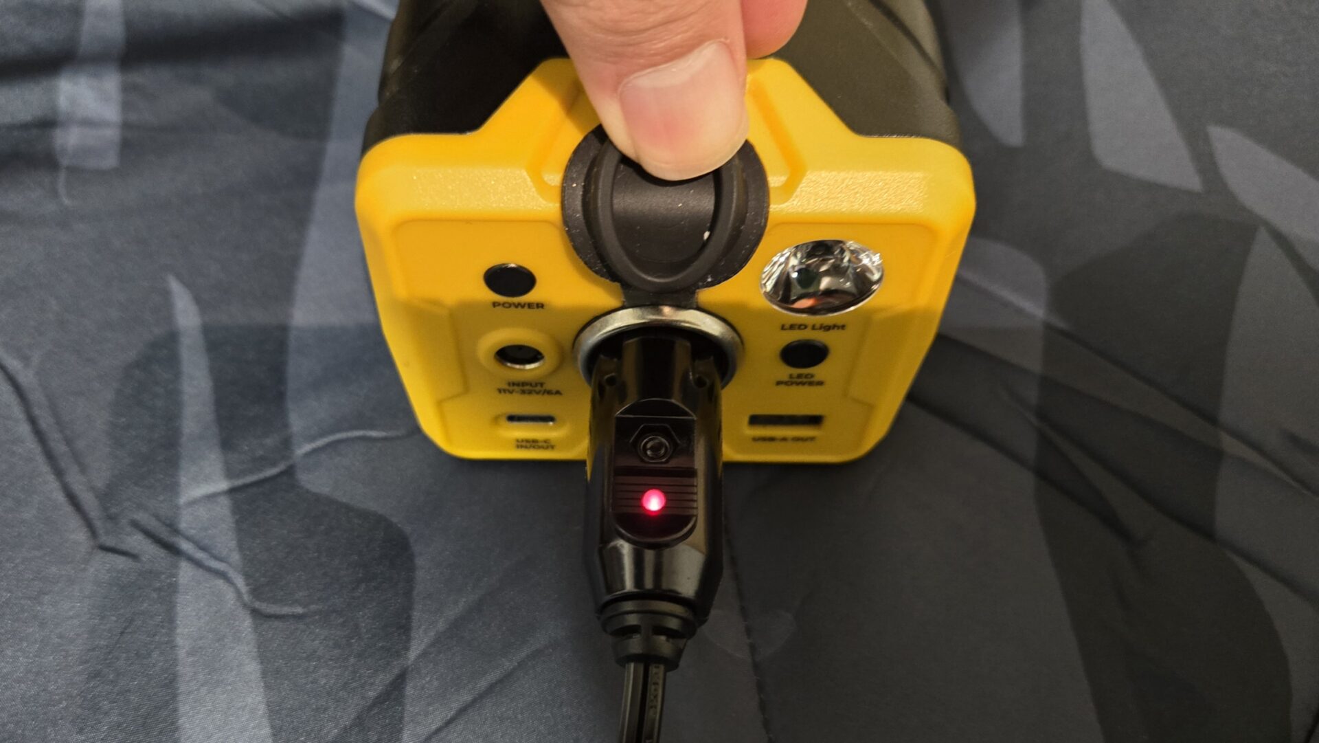 黄色と黒のポータブル電源に車用充電ケーブルを接続し充電中