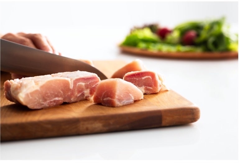 まな板の上で包丁を使って肉を切る様子