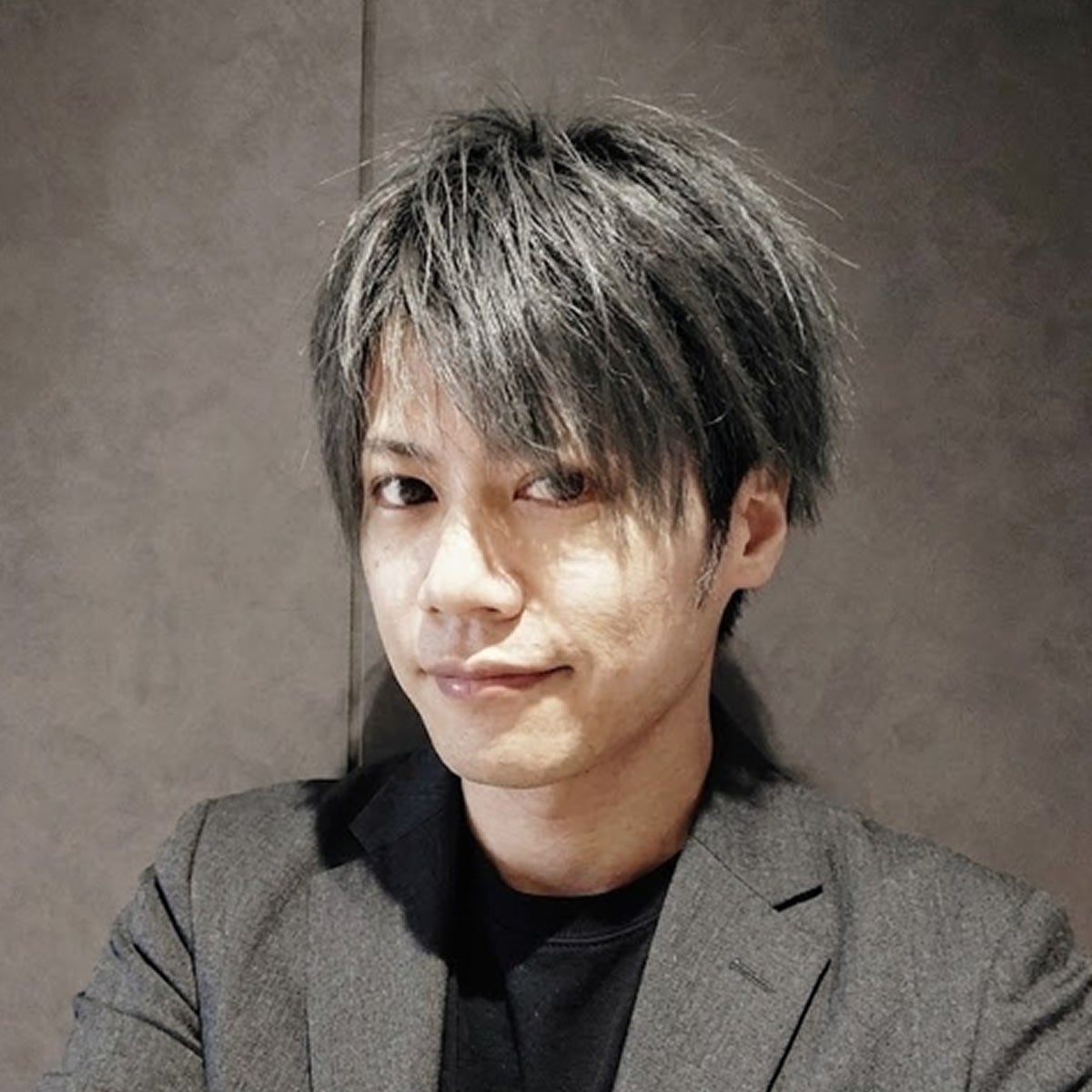 ジャケットを着用した人物の上半身を正面から写したポートレート写真。