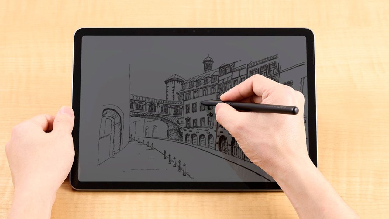 タブレット端末の画面にペンで街並みのイラストを描画している手元の様子