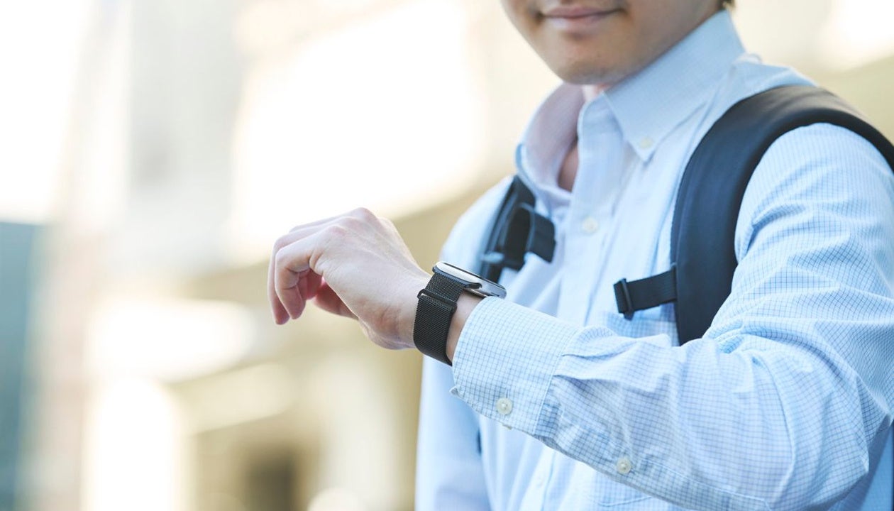 黒いメッシュ調バンドのスマートウォッチを手首に着用した人物の斜め前からの姿