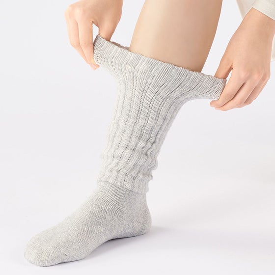 着用したグレーの靴下の履き口を両手で広げている様子