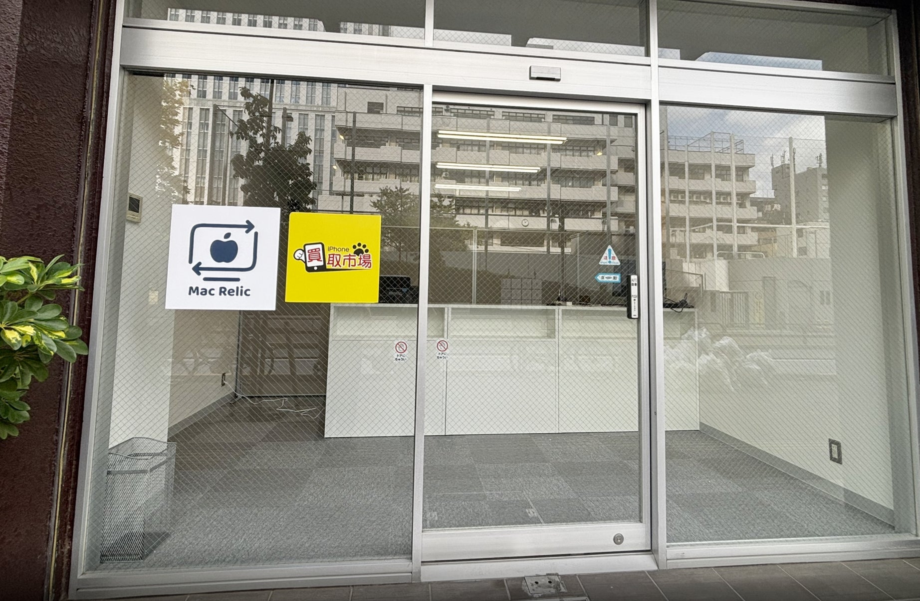 ガラス張りの店舗入口。ガラス戸にロゴマークが貼られ、奥にカウンターが見える。