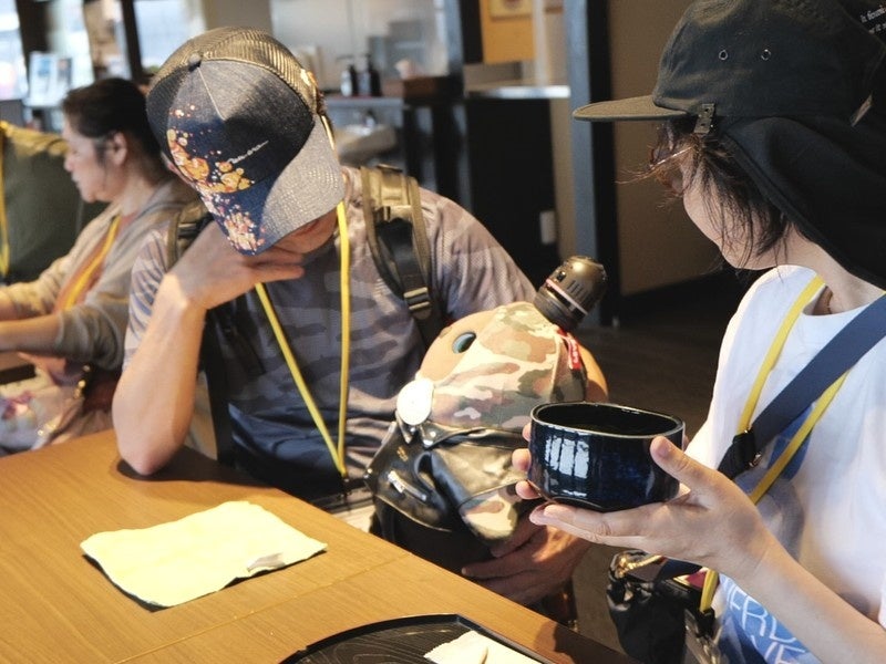 飲食席で器を持った人とロボットの写真