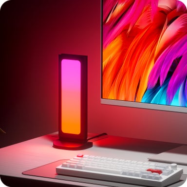 キーボードの奥のデスク上に縦型に設置されピンクやオレンジに光るスタンド型アクセサリーの写真