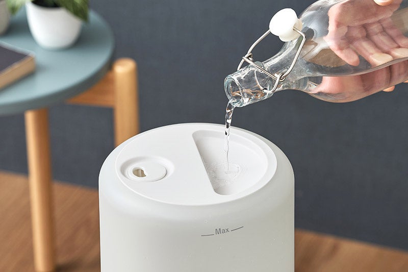 ガラス瓶から加湿器の本体上部の給水口へ直接水を注ぎ入れている様子
