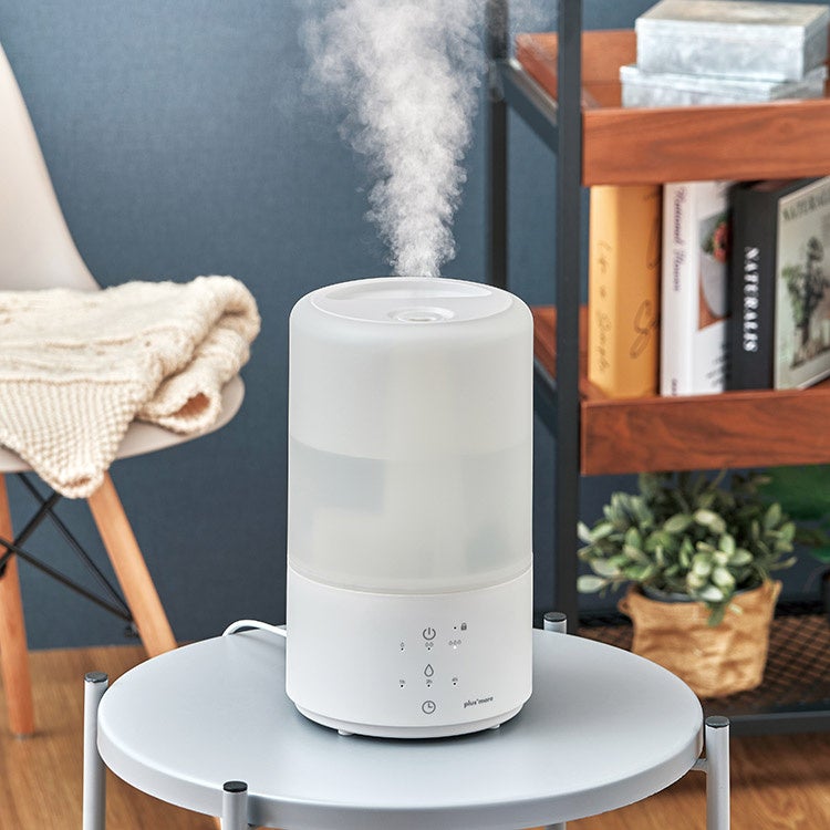 丸テーブルの上に置かれた白い円筒形加湿器から蒸気が出ている様子