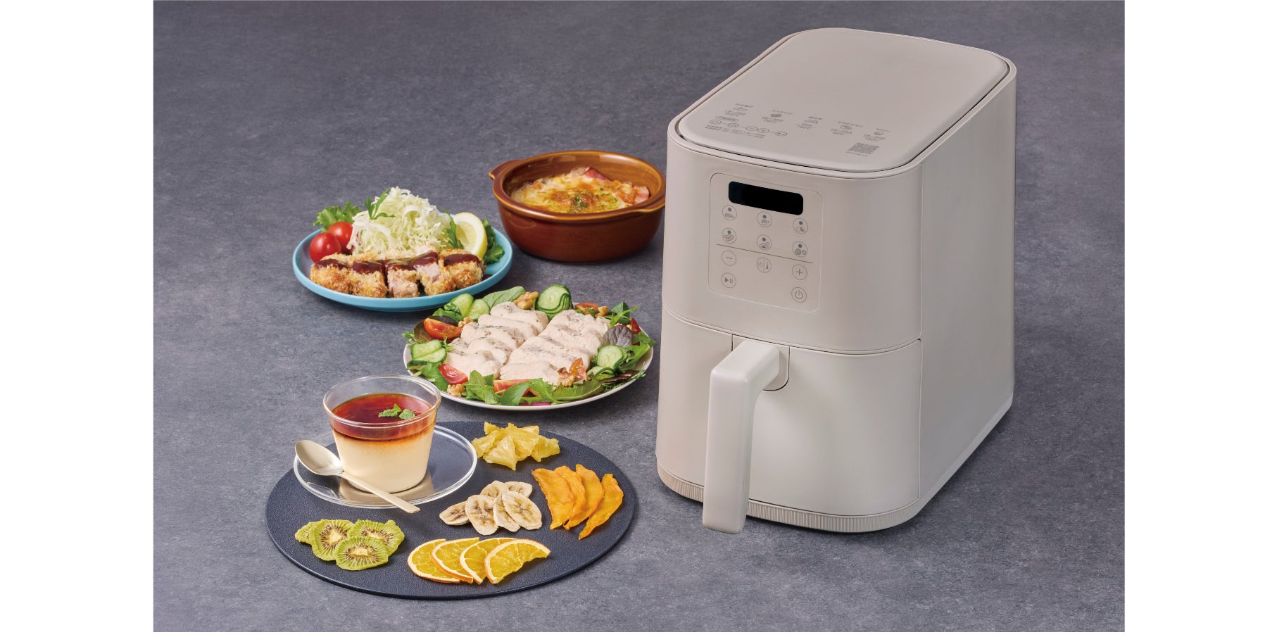 ベージュ系の調理家電本体の横に、カツやサラダチキン、ドライフルーツ、プリンなどの料理が並んだ様子