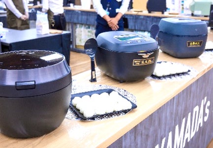 カウンターに並ぶ調理家電とおにぎりの試食皿を捉えた写真