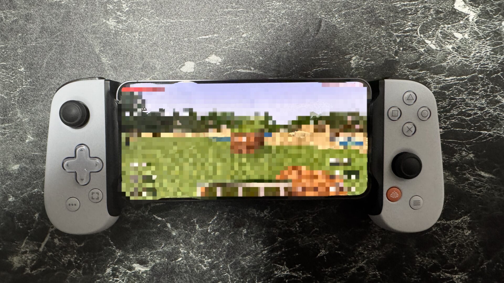 スマホに取り付けたゲーム用コントローラーでマインクラフトを遊んでいる様子