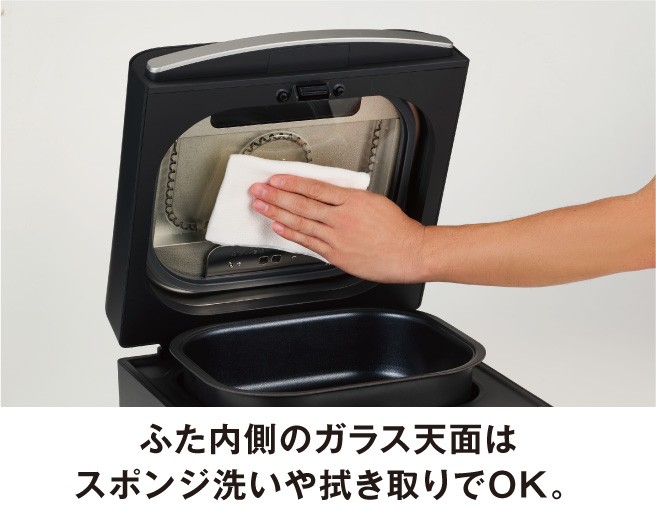 ふた内側のガラスをスポンジで拭く手元