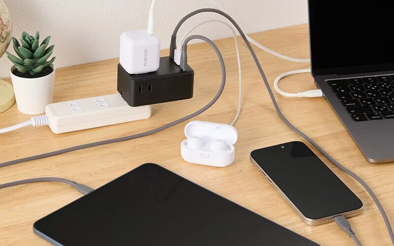 ELECOM充電器と電源タップを使いノートパソコンスマートフォンワイヤレスイヤホンタブレットなど複数の電子機器を机の上で同時に充電する様子